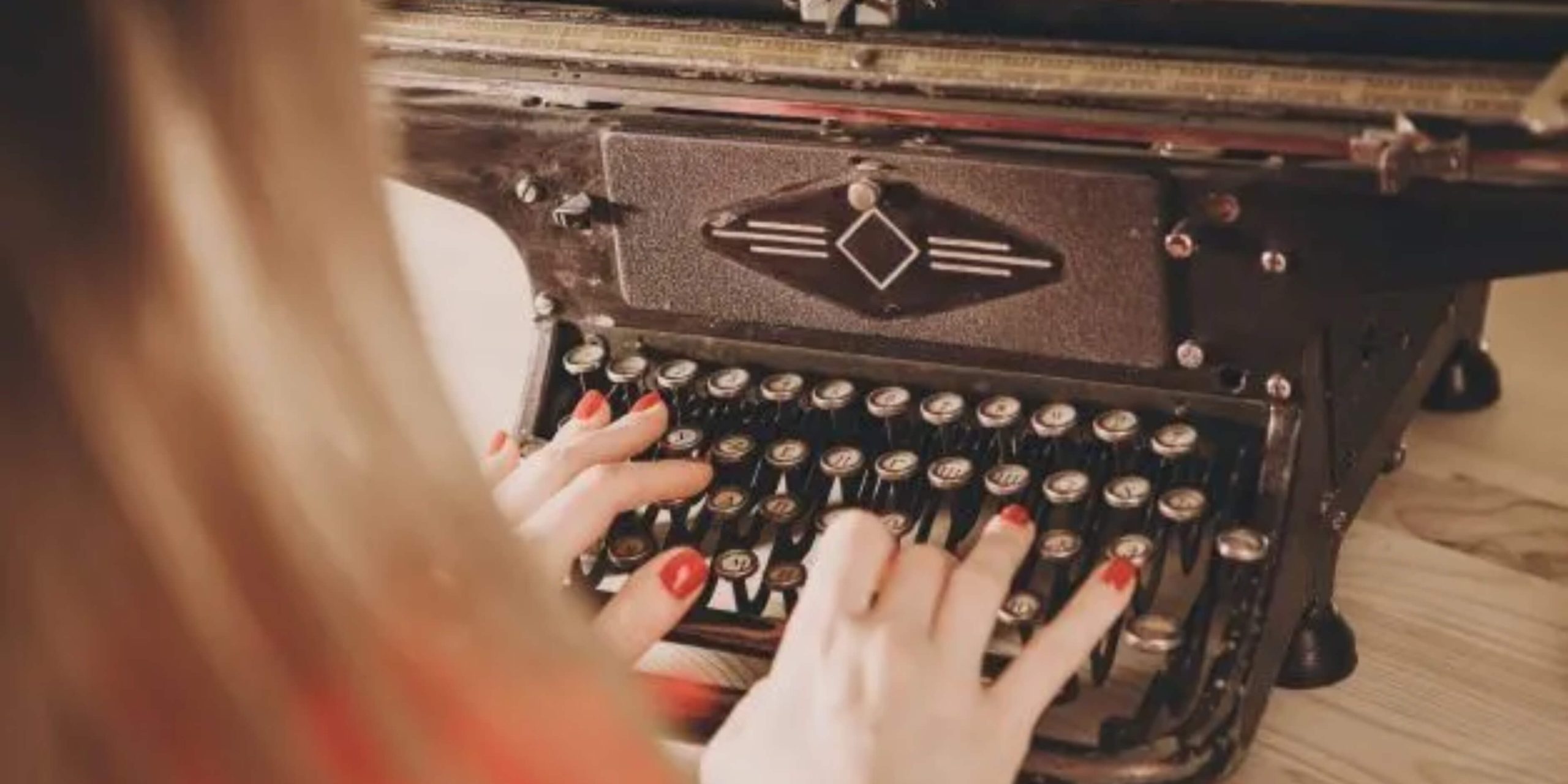 Hands typing on an antique typewriter, emphasizing the roots of modern typing technology.
