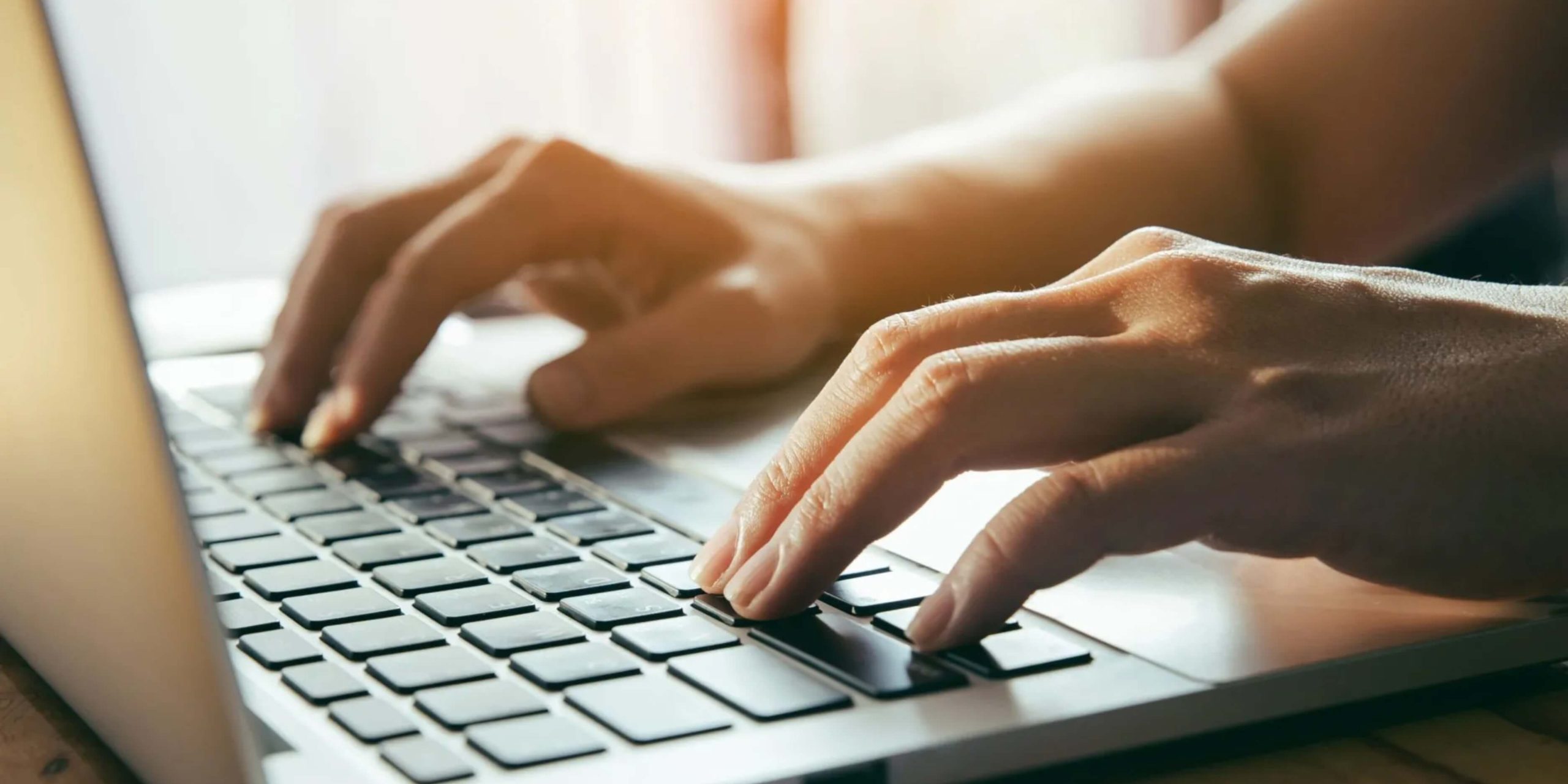A person typing on a modern laptop, representing today’s fast, portable typing environments.