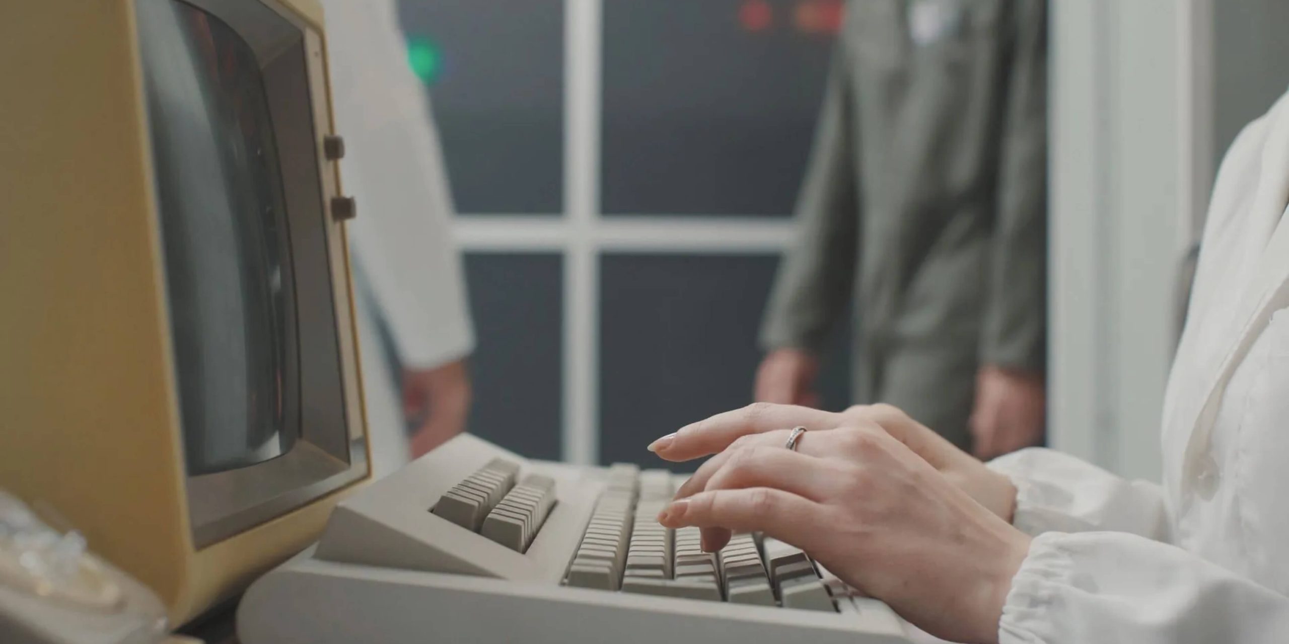 Person typing on a 1980s-era personal computer, showcasing early computer-based typing practices.
