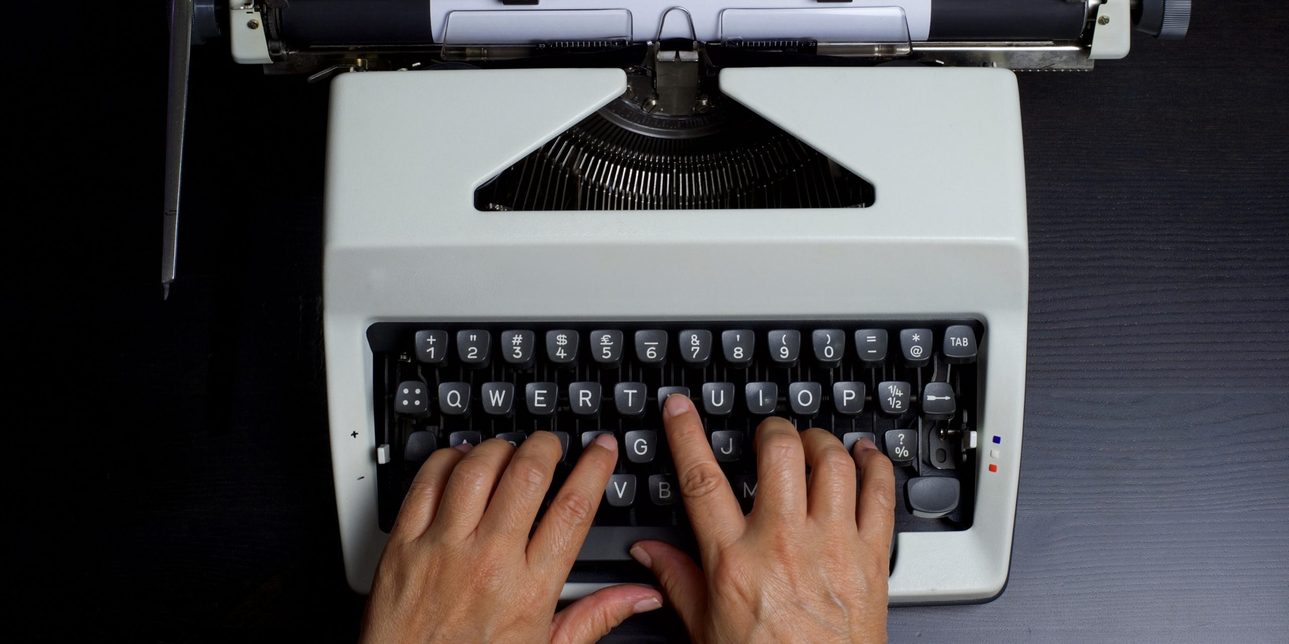 Individual typing on an electric typewriter, illustrating the shift from manual to digital typing tools.