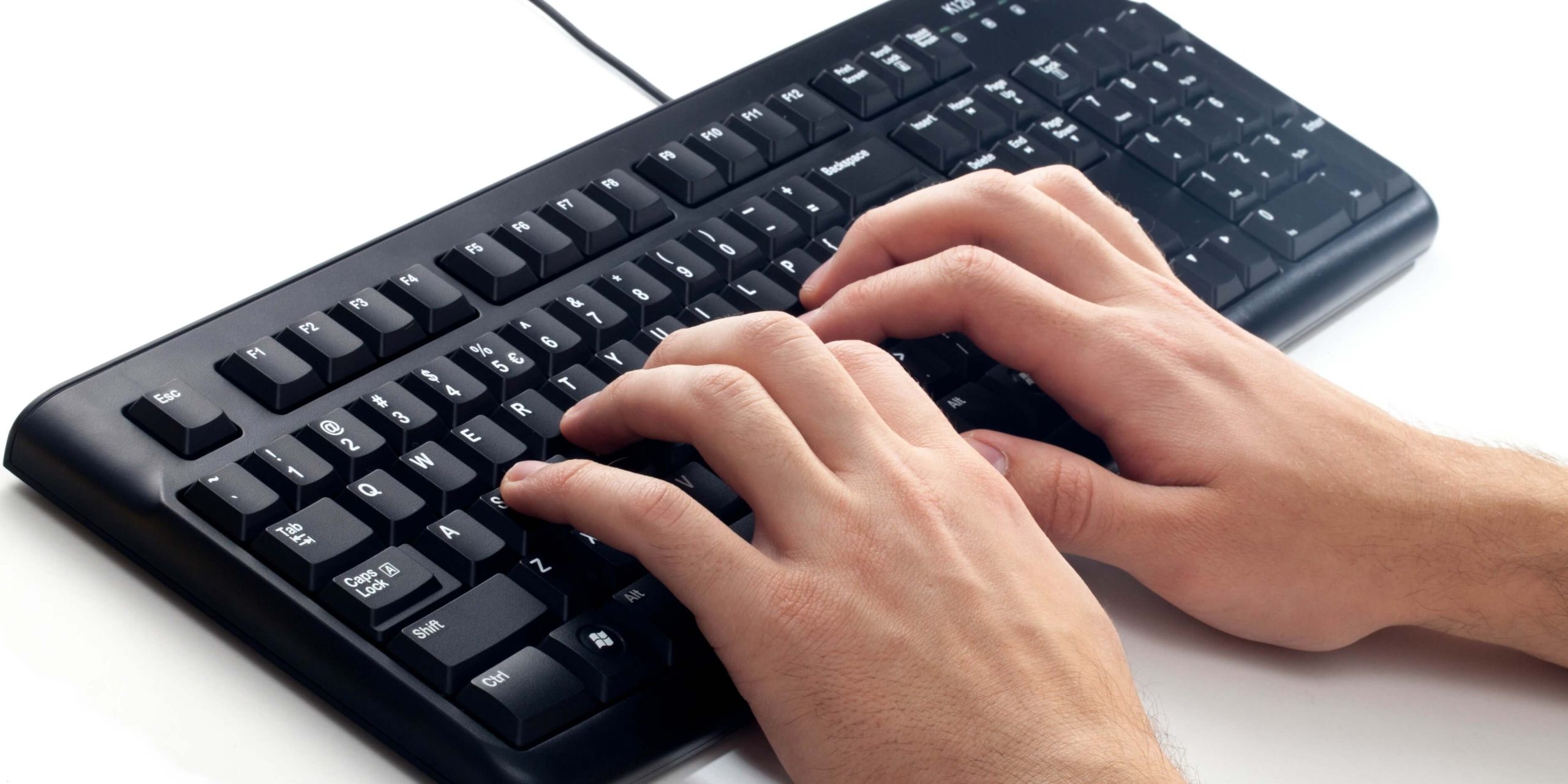 Fingers typing on a QWERTY keyboard, the standard layout used in modern touch typing and speed typing competitions.