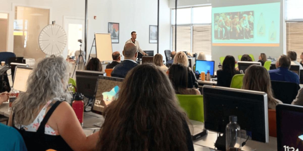 An instructor presenting to adult learners in a computer-based classroom at Academy of Learning Career College, highlighting structured support and multi-sensory learning environments that enhance retention.