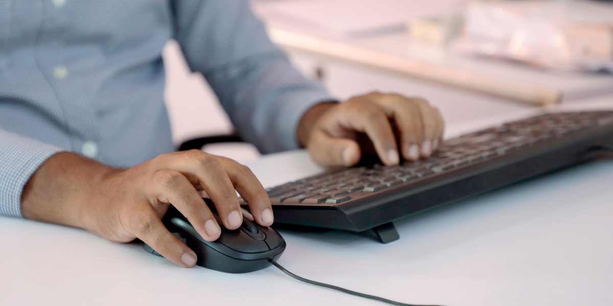 Close-up of hands using ergonomic keyboard setup with mouse, showing correct hand position to meet typing speed requirements by profession in Canadian workplaces.