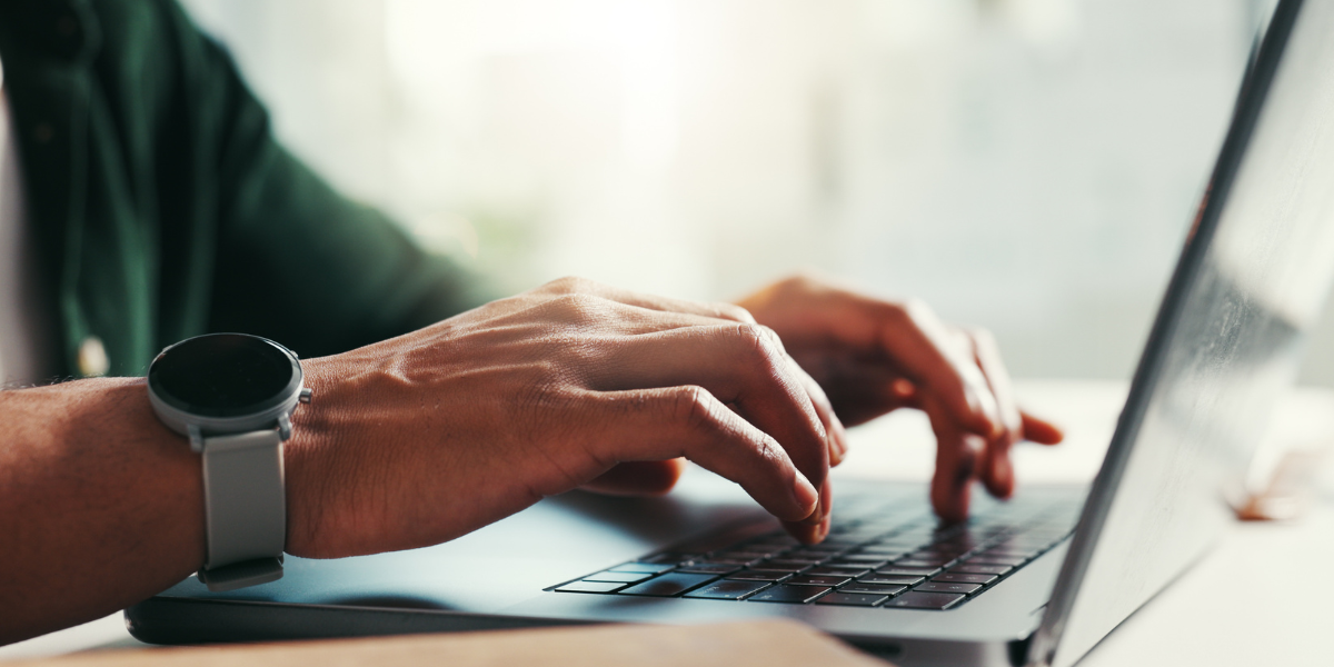Person demonstrating professional typing skills for remote work on a laptop, showcasing proper finger positioning for online touch typing courses for beginners.